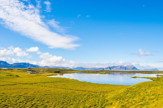 Paysage verdoyant avec lac et ciel avec nuages Belle Helgafell, Islande avec collines et océan