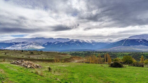 Paysage verdoyant avec des montagnes enneigées et ciel dramatique à Somosierra Madrid. L'Europe .