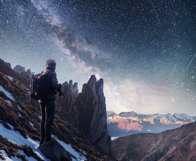Paysage avec voie lactée, étoiles du ciel nocturne et silhouette d'un homme photographe debout sur la montagne.