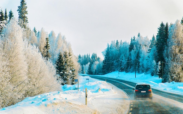 Paysage avec voiture sur route enneigée en Finlande. Voyage de vacances sur l'autoroute avec la nature. Paysage avec route d'hiver en voyage de vacances pour les loisirs. Balade en mouvement en Europe. Transport sur allée.