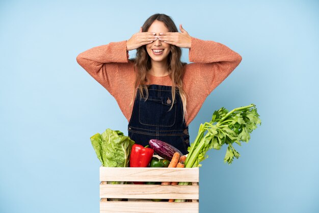 Paysanne avec boîte de légumes couvrant ses yeux