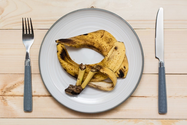 Peau de banane pourrie sur une assiette avec des couverts