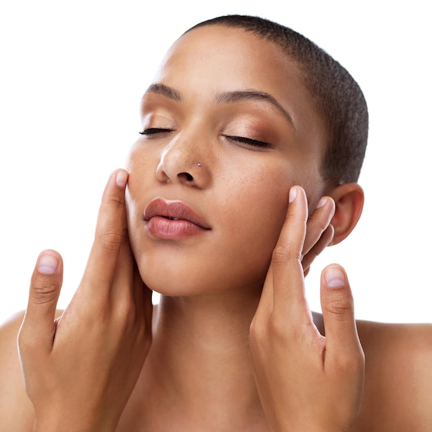 Avec une peau comme ça, tout est possible Prise de vue en studio d'une belle jeune femme touchant son visage en se tenant debout sur un fond blanc