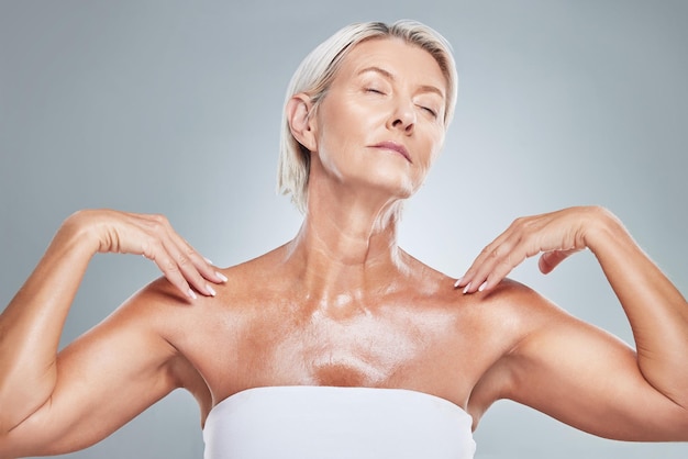 Peau de soin et femme âgée en studio pour la beauté et le bien-être sur fond gris Détendez-vous le corps et le modèle âgé posant avec un éclat brillant et une peau saine après un produit anti-âge