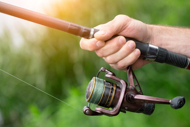 Photo pêche d'été sur le lac la main d'un homme tient un gros plan de canne à pêche