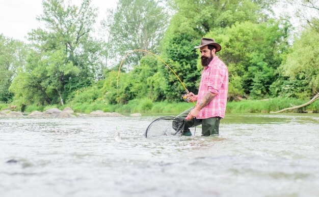 La pêche fournit cette connexion avec le monde vivant tout entier Passe-temps de pêche Pêcheur barbu attrapant des truites avec un filet La pêche est un sport de plein air récréatif accessible étonnant Trouvez la tranquillité d'esprit