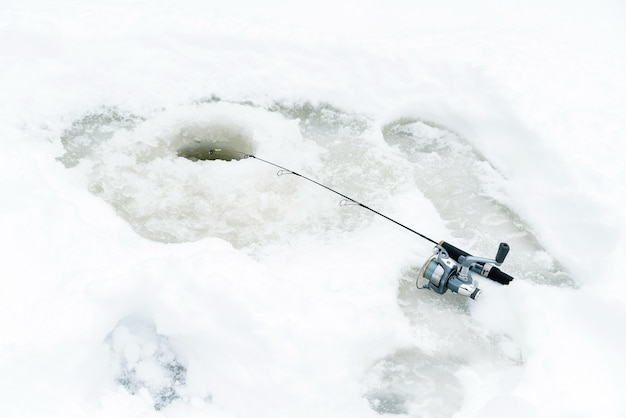 Pêche hivernale sur glace, appât jiggling dans un trou de glace.