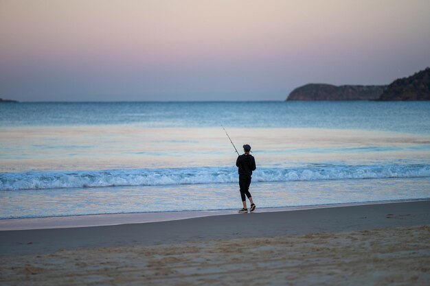 pêche sur la plage dans les vagues de l'océan au crépuscule pendant les vacances d'été