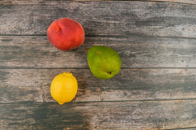 Pêche, poire, citron sur une table en bois