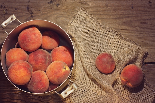 Pêches dans une casserole et petites fleurs jaunes sur la table.