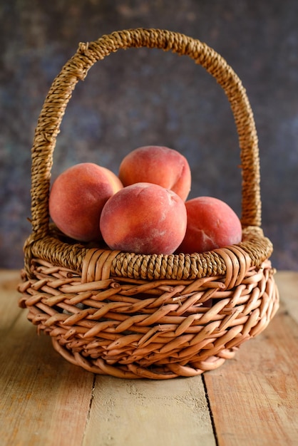 Pêches dans un panier en osier sur une table en bois