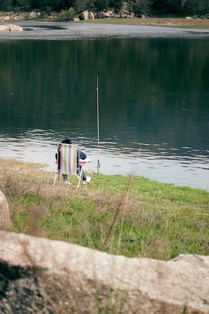 Un pêcheur assis au bord d'un lac avec une canne à pêche