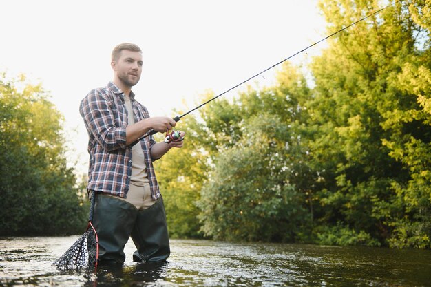 Le pêcheur attrape une truite sur la rivière en été