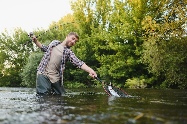 Le pêcheur attrape une truite sur la rivière en été