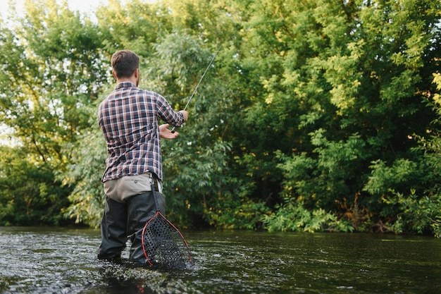 Le pêcheur attrape une truite sur la rivière en été