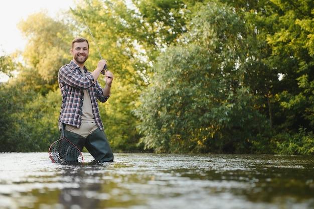 Le pêcheur attrape une truite sur la rivière en été