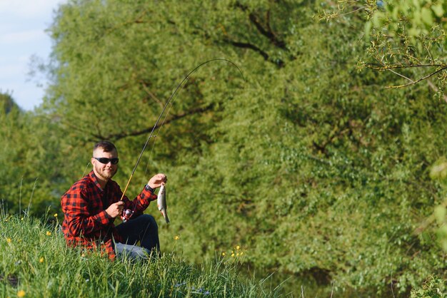 Pêcheur au bord de la rivière avec une prise de poisson