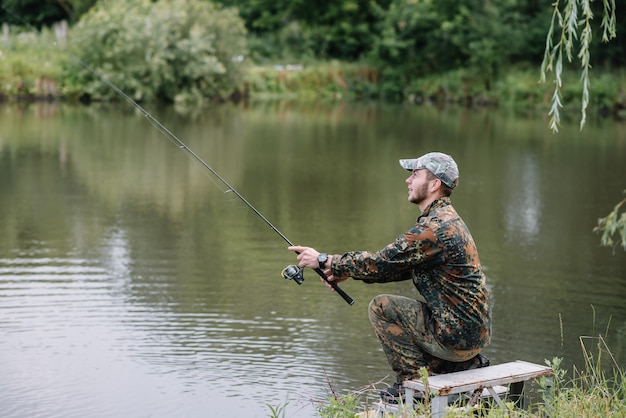 Un pêcheur avec une canne à pêche sur la rive du fleuve