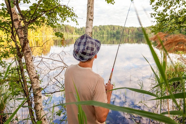 Pêcheur avec des cannes à pêche pêche dans un lac ou une rivière