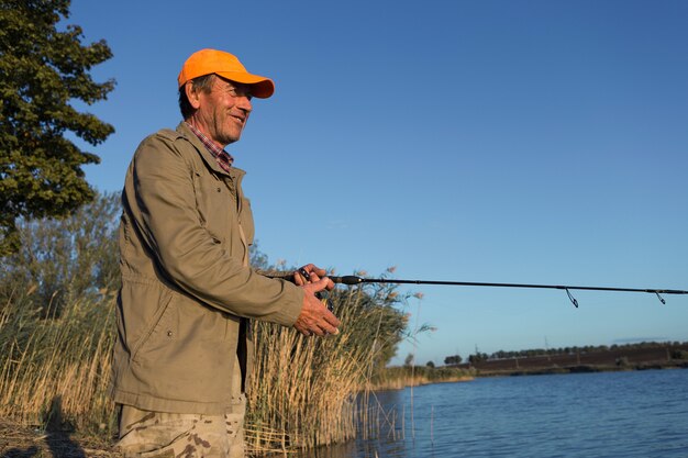 Pêcheur debout au bord de la rivière et essayant d'attraper un poisson. Sport, loisirs, mode de vie.