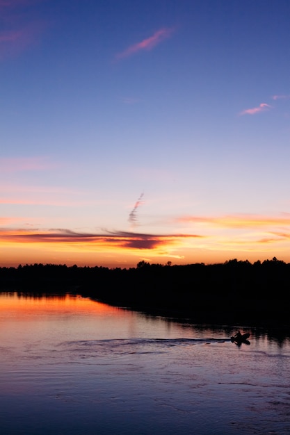 Un pêcheur flottant sur la rivière le soir