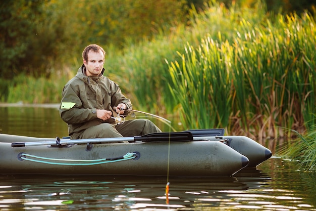 Pêcheur sur le fond de la forêt d'automne Pêcheur dans sa main tenant la filature et le poisson