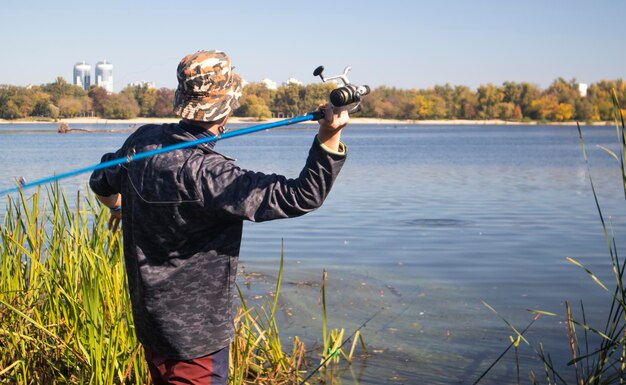 Un pêcheur a jeté une canne à lancer dans un lac ou une rivière par une journée ensoleillée Pêche à terre Un pêcheur