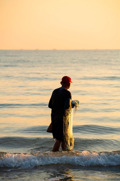 Photo le pêcheur a jeté un filet la mer le matin, au lever du soleil