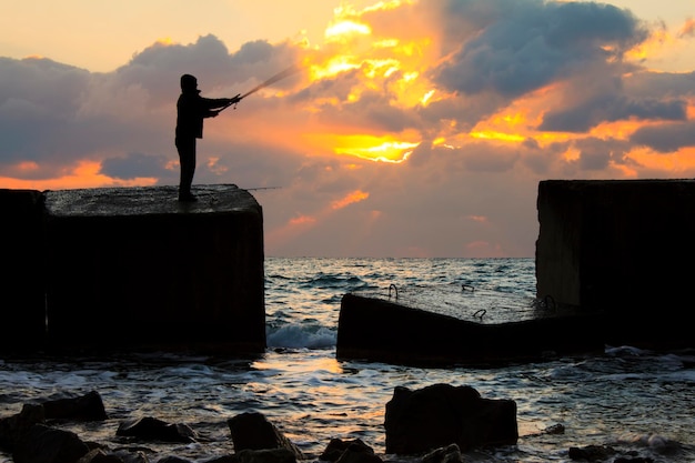 Pêcheur sur la jetée au coucher du soleil