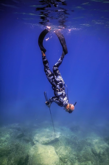 Le pêcheur à la lance nage sur le fond rocheux de la mer