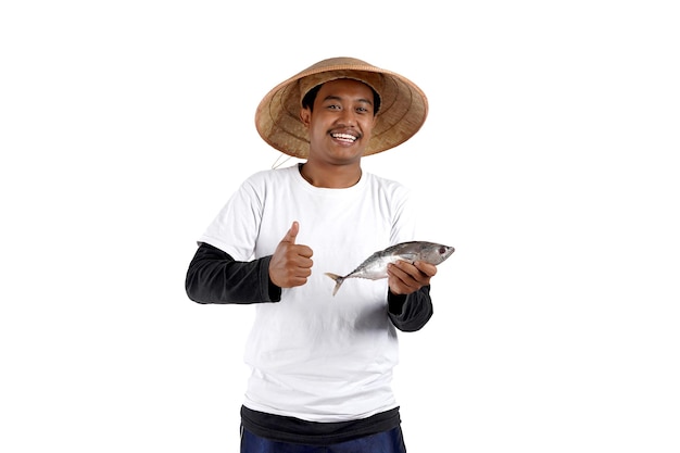 Un pêcheur local asiatique tenant du poisson et faisant des gestes d'accord avec sa main. Photo de studio en gros plan