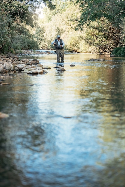 Pêcheur à la mouche utilisant une canne à pêche à la mouche dans une belle rivière