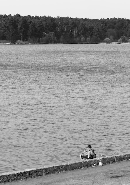 Pêcheur noir et blanc sur fond de berge