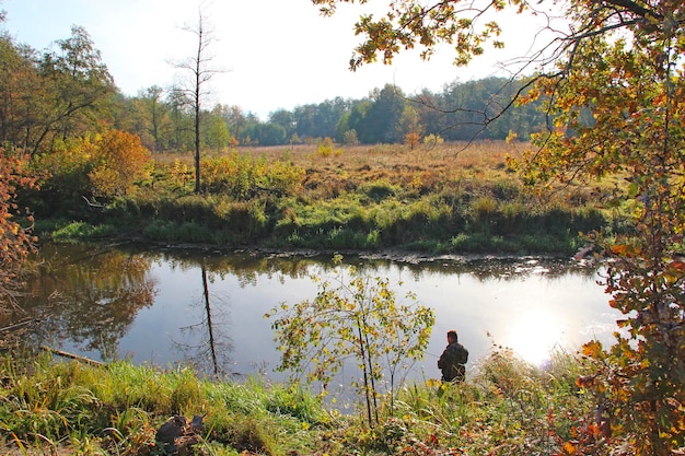 Pêcheur pêchant sur le lac d'automne Pêcheur debout au bord de la rivière et essayant d'attraper du poisson Passer du temps libre Passe-temps masculin Loisirs Concept de style de vie Pêcheur sur la rive de la rivière en automne