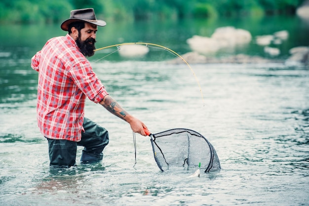 Pêcheur pêchant sur un rever Homme pêcheur détendu avec une canne à pêche un jour d'été