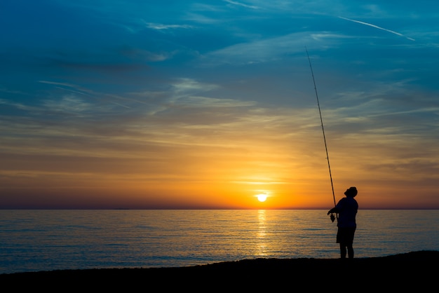 Pêcheur sur la plage au coucher du soleil