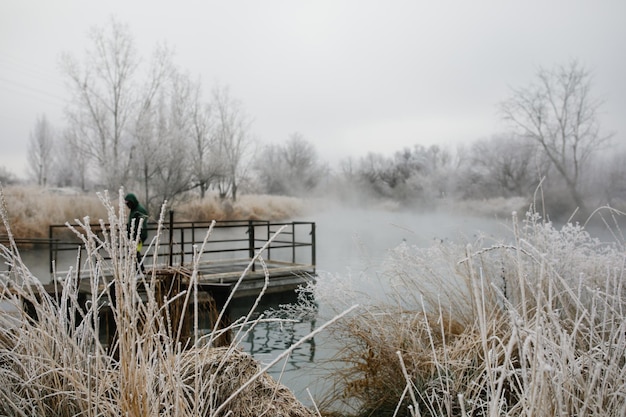 Pêcheur sur un quai par un froid matin d'hiver sur un étang brumeux et givré à Nampa, Idaho