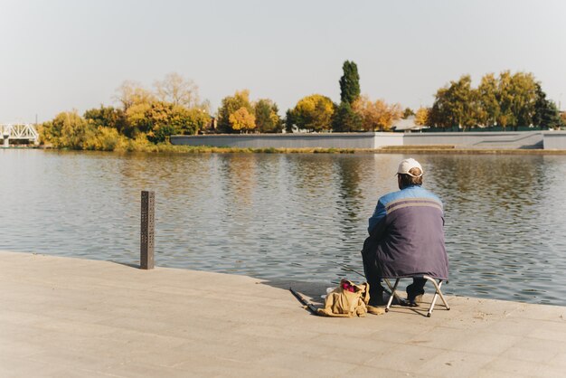 Pêcheur sur le quai de la ville dans le contexte des arbres d'automne