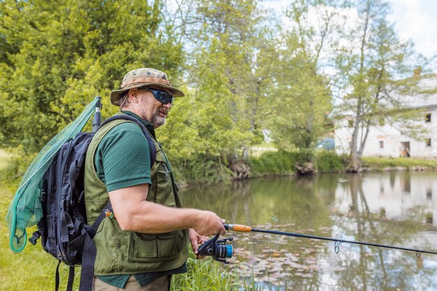 Pêcheur récréatif sur la rive d'une rivière essayant d'attraper un poisson.