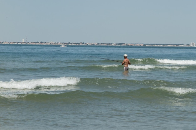 Un pêcheur à la retraite dans l'eau sur la plage