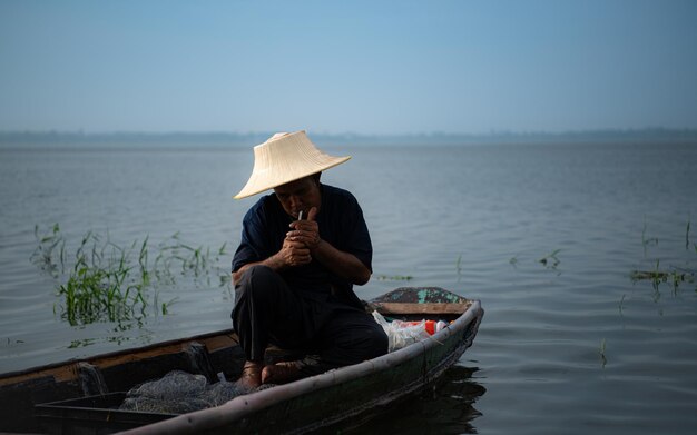 Photo un pêcheur se détend dans un bateau sur le lac tout en fumant.