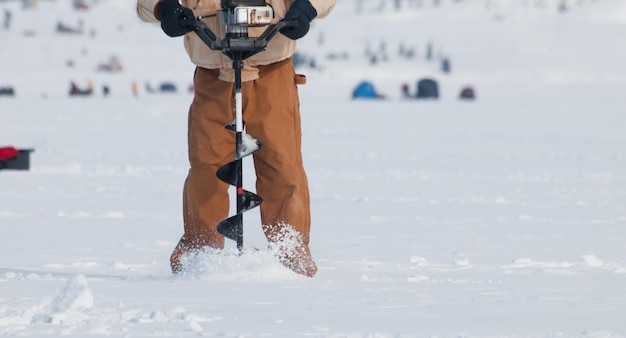 Pêcheur avec une tarière sur le lac gelé Granby, Colorado.