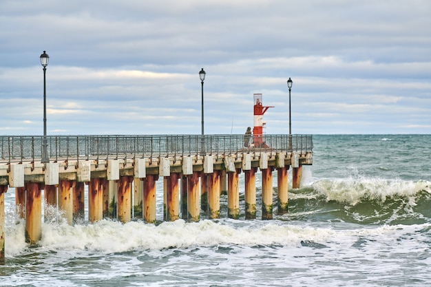 Pêcheur en tenue de camouflage et pêche sur la jetée avec phare