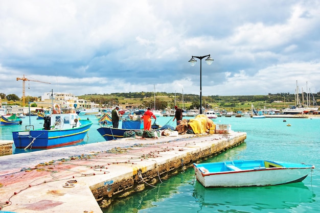 Pêcheurs sur le bateau coloré de Luzzu au port de Marsaxlokk sur l'île de Malte