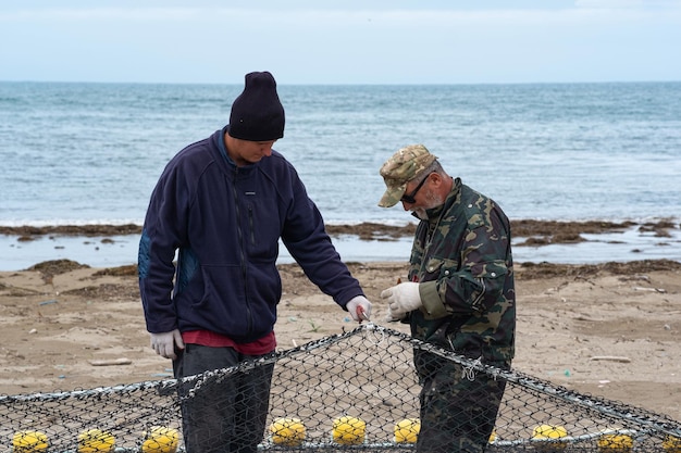 Les pêcheurs vérifient et réparent le filet de pêche sur le rivage