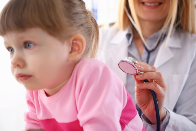 Le pédiatre écoute les poumons d'une petite fille avec stéthoscope