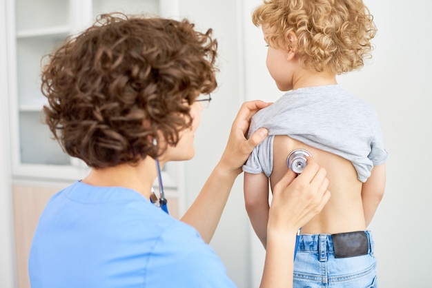 Pédiatre à l'écoute de la respiration des garçons