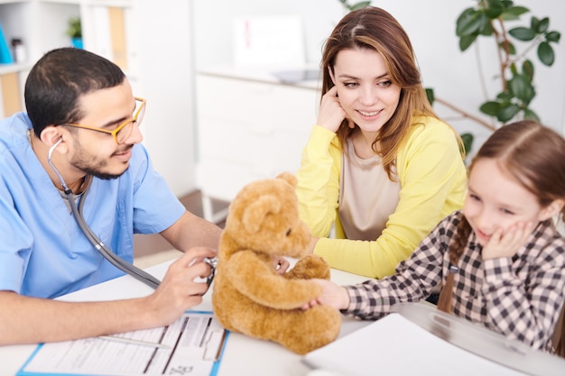 Pédiatre examinant l'ours en peluche