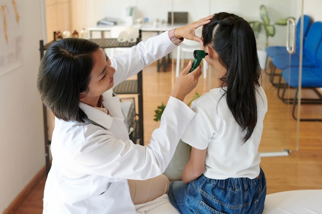 Photo un pédiatre examine les oreilles d'une fille.