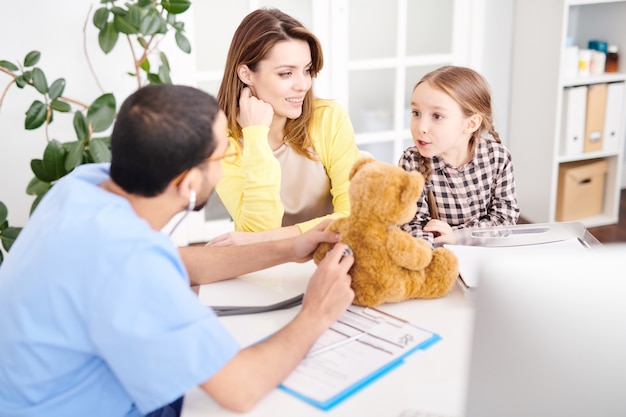 Pédiatre ludique examinant l'ours en peluche